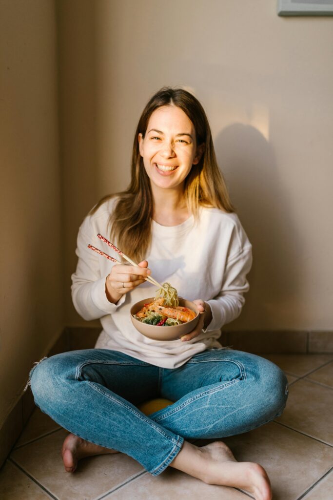 Lachende Frau genießt ein gesundes Essen in einer warmen, natürlichen Atmosphäre
